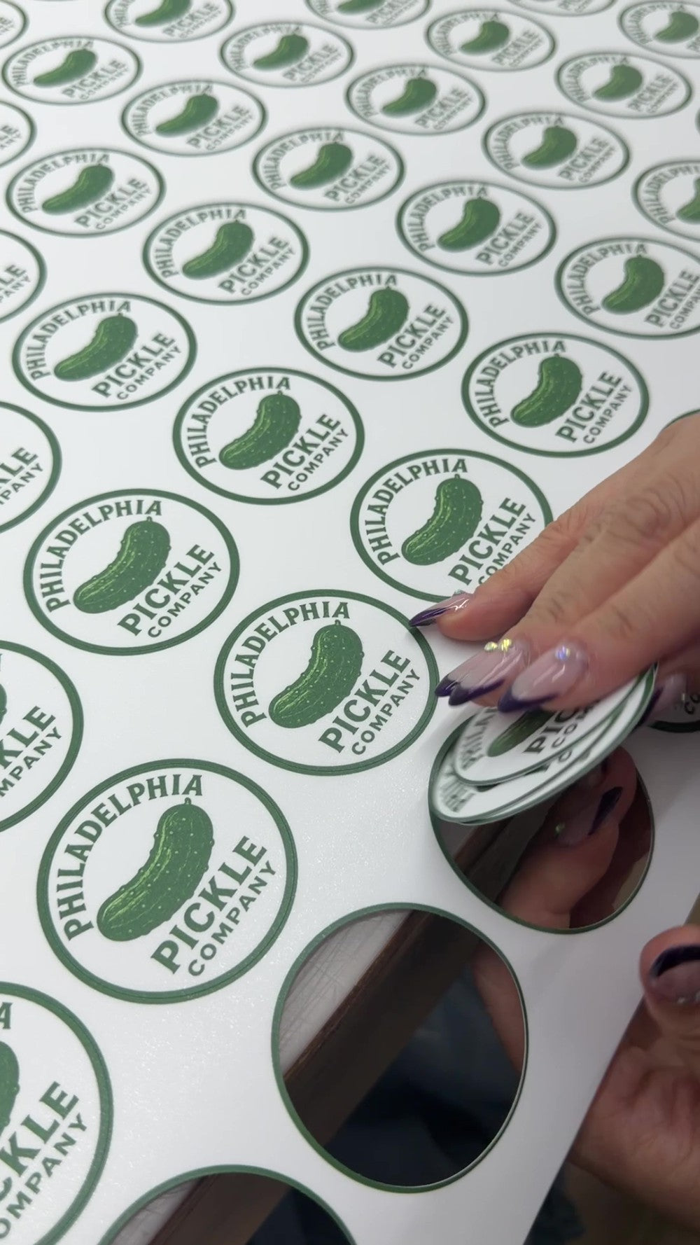 Green custom logo stickers being finished by hand