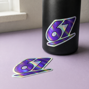 Sample mockup of a purple 67 holographic sticker on a black bottle with a matching loose sticker.
